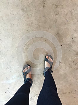 Selfie of female feet wearing flip flops on concrete floor background