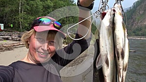 Selfie of a fisherwoman with a fresh catch. Fishing for grayling. Slow motion