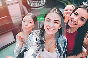 Selfie of four girls having fun together. They are posing with smile and sending kisses to camera.