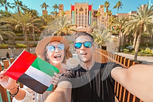 Selfie of a loving couple of man and woman holding UAE national flag. Travel in Dubai and United Arab Emirates