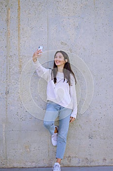 Selfie mania! Excited young girl is making a photo with smartphone. outdoors - Image