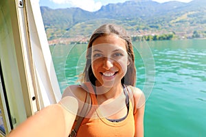 Selfie photo of young model woman on travel cruise vacation in orange tank top enjoying the evening on getaway holidays.