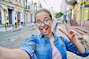 Selfie portrait of beautiful cheerful teenage girl, outdoor on city street