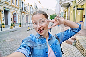 Selfie portrait of beautiful cheerful teenage girl, outdoor on city street