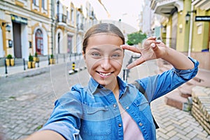 Selfie portrait of beautiful cheerful teenage girl, outdoor on city street