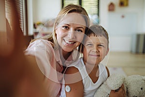 Selfie portrait of mother and diabetic boy with a continuous glucose monitor on his arm.