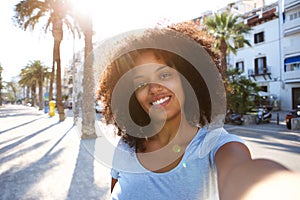 Selfie portrait of woman smiling outside with curly hair