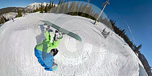 SELFIE: Pro freeride snowboarder jumps in the air off a kicker and does a flip.