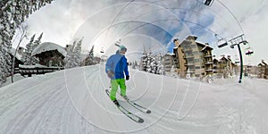 SELFIE: Skier cruises along the groomed slope running between ski resort lodges