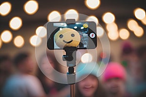 Selfie of a smiley face on a smartphone in front of a group of people