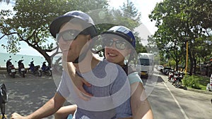 SELFIE: Smiling man and woman ride a motorcycle together along sunny beach road.