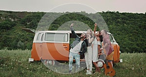 Selfie time for group of friends at the nature, taking pictures from phone, beside of their vintage van.