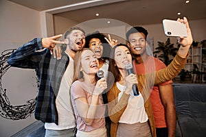 Selfie time. Group of young happy multicultural friends taking a selfie using smartphone while spending time together