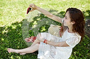 Selfie time.Joyful attractive young woman making selfie by her smart phone in the summer park