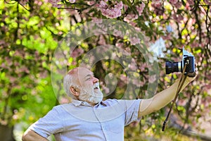 Selfie time. photographer man take sakura cheery blossom photo. Cherry blossoming garden. photographer taking photos of