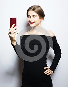 Selfie time. Young smiling blond woman doing selfie on white background.