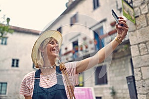 Selfie time. Young woman with mobile phone taking selfie on street. Summer holiday. Lifestyle, fashion, holiday concept