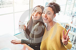 This is a selfie of two beautiful girls that look so amazing and happy at the same time. They are in cafe drinking some