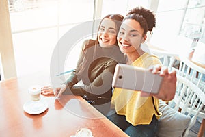 This is a selfie of two beautiful girls that look so amazing and happy at the same time. They are in cafe drinking some