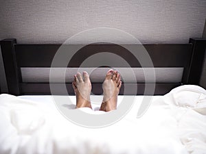 Selfie woman bare feet under white blanket on bed