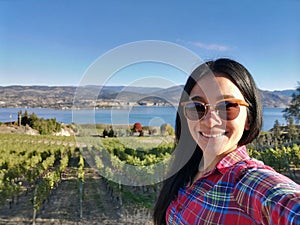 Selfie of a young Asian woman at vineyards landscape in Naramata, Okanagan valley, British Columbia, Canada. Canadian agriculture