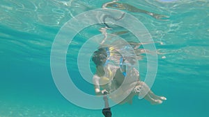 Selfie of a young couple swimming underwater in a tropical lagoon. Two people have fun with an underwater camera while