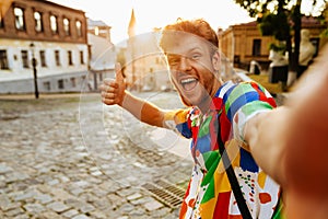 Selfie of young handsome smiling redhead man showing thumb gesture