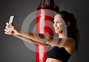 Before and after selfies are where its at. an attractive young female boxer taking selfies while training in the gym.