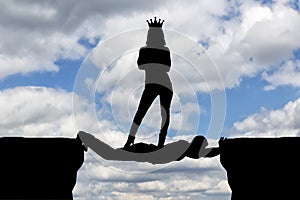 Selfish woman with a crown standing on a man in the form of a bridge over an abyss photo