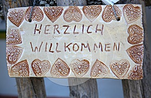 Selfmade sign with the writing `Herzlich willkommen` in German language