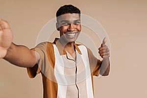 Selfportrait of young handsome smiling african man doing thumb gesture