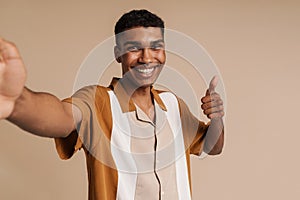 Selfportrait of young handsome smiling african man doing thumb gesture photo