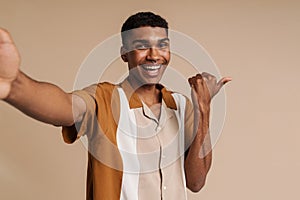 Selfportrait of young handsome smiling african man pointing aside