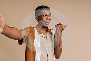 Selfportrait of young handsome smiling african man pointing aside