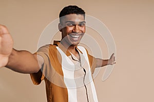 Selfportrait of young handsome smiling african man with raised hand