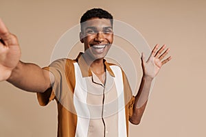 Selfportrait of young handsome smiling african man waving raised hand