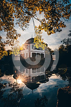 Seligenstadt moated castle in nature with a lake. with bushes and trees, reflection of the castle in the blue water