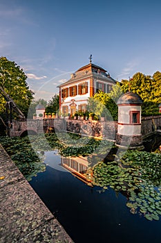 Seligenstadt moated castle in nature with a lake. with bushes and trees, reflection of the castle in the blue water