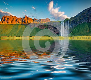 Seljalandfoss Waterfall reflected in the calm waters of Seljalandsa rive.