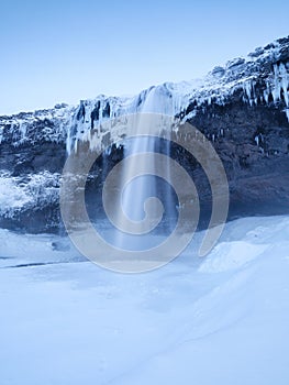 Seljalandsfoss waterfall, Iceland. Icelandic winter landscape. High waterfall and rocks. Snow and ice.