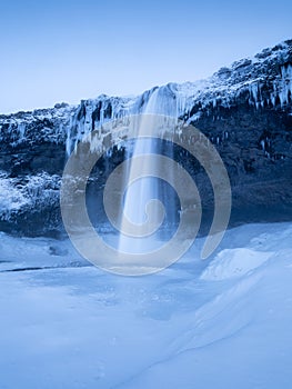 Seljalandsfoss waterfall, Iceland. Icelandic winter landscape. High waterfall and rocks. Snow and ice.