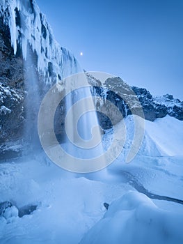 Seljalandsfoss waterfall, Iceland. Icelandic winter landscape.  High waterfall and rocks. Snow and ice. Powerful stream of water f