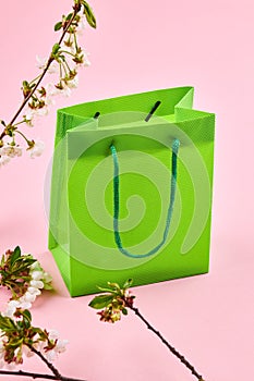 sell concept. green shopping bag on a pink background. decorating with spring flowers