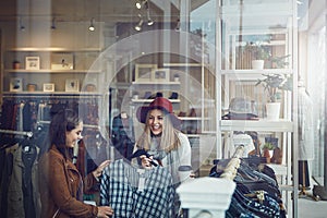 They sell the finest quality clothing here. two best friends out shopping in a clothing store.