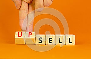 Sell or upsell symbol. Concept word Sell Upsell on wooden cubes. Businessman hand. Beautiful orange table orange background.