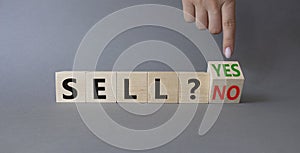 Sell Yes or No symbol. Businessman Hand points at wooden cubes with words Sell No or Sell Yes. Beautiful grey background. Business