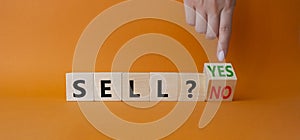 Sell Yes or No symbol. Businessman Hand points at wooden cubes with words Sell No or Sell Yes. Beautiful orange background.