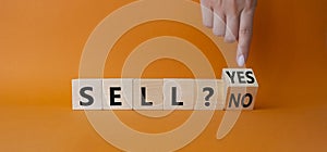 Sell Yes or No symbol. Businessman Hand points at wooden cubes with words Sell No or Sell Yes. Beautiful orange background.