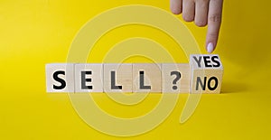 Sell Yes or No symbol. Businessman Hand points at wooden cubes with words Sell No or Sell Yes. Beautiful yellow background.