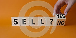 Sell Yes or No symbol. Businessman Hand turns cubes and changes words Sell No to Sell Yes. Beautiful orange background. Business